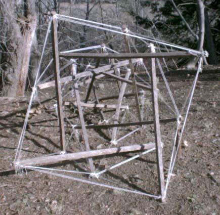 axial view of four-fold garden-stake-and-nylon-twine tensegrity obelisk lying on its side outdoors